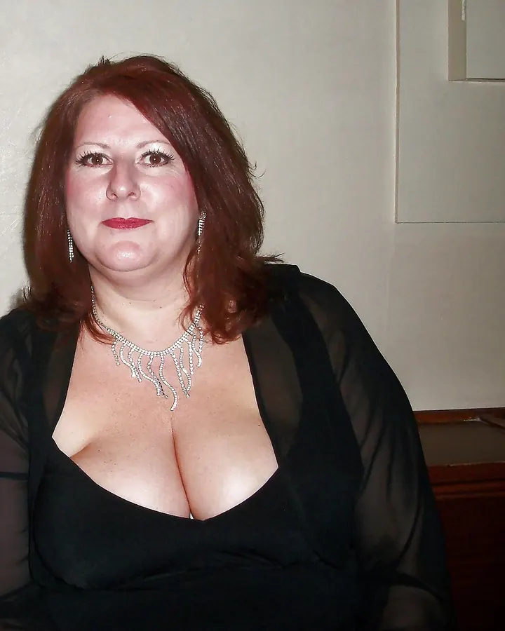 Femme en robe noire, collier scintillant, souriante, regard direct