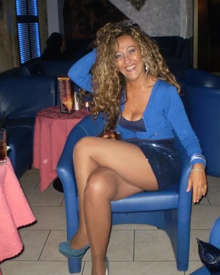 Femme aux cheveux châtains mi-longs portant un haut noir, assise, regardant l'appareil photo avec un sourire discret.