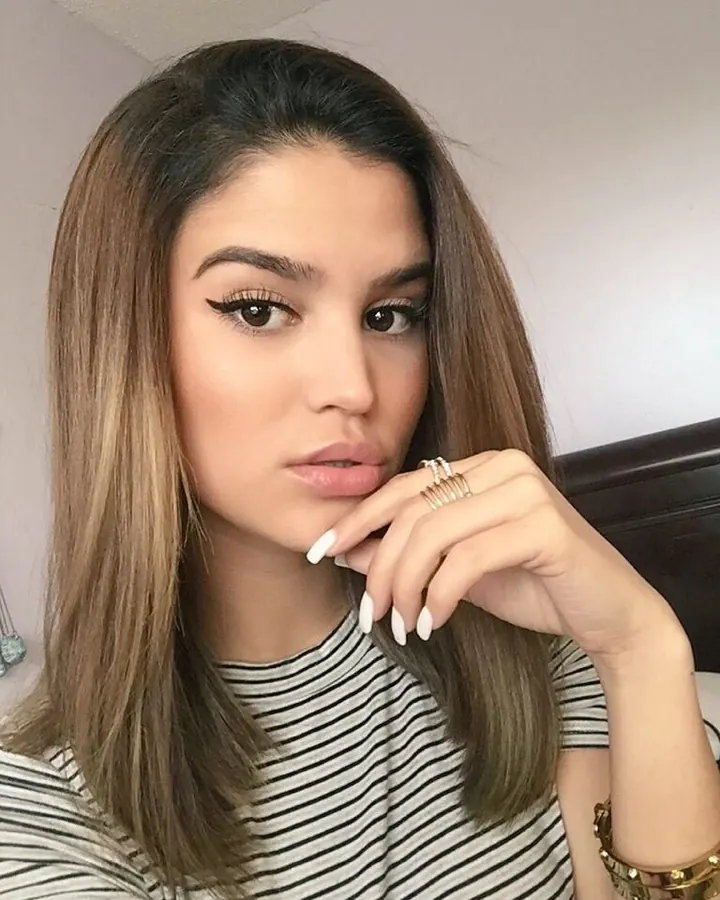 Femme en chemise rayée, posant près d'un lit, main sur la bouche