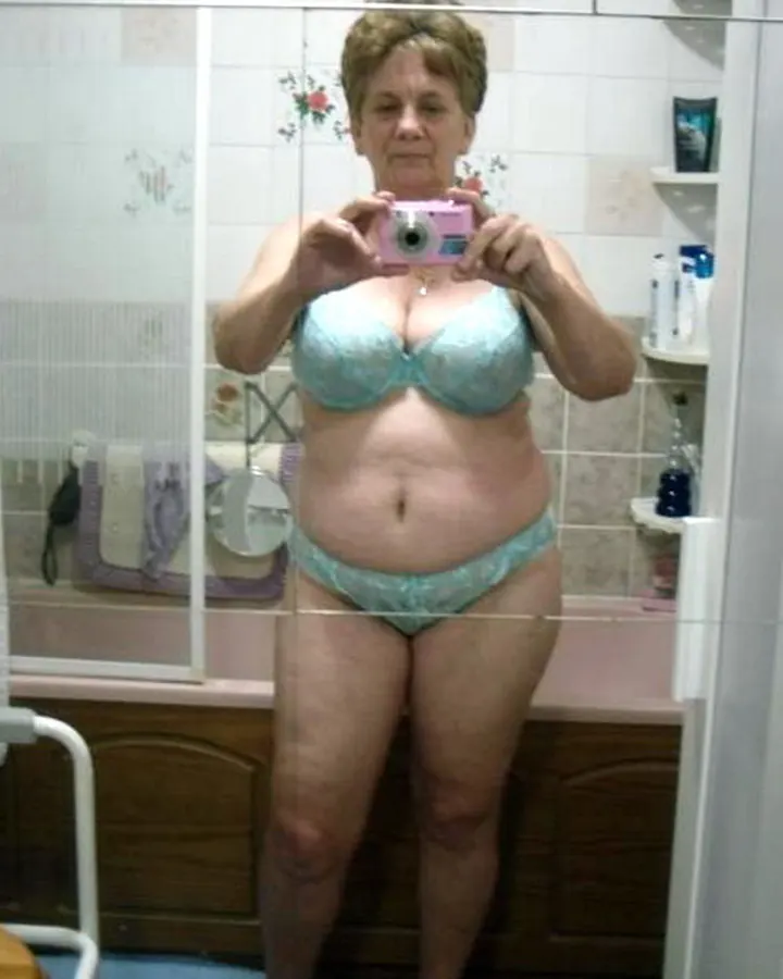 Femme européenne aux cheveux blonds, en haut noir et culotte léopard, tenant son vêtement ouvert.