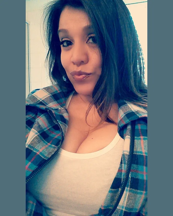 Femme aux cheveux bruns en sous-vêtements noirs, regardant la caméra, main sur le ventre.