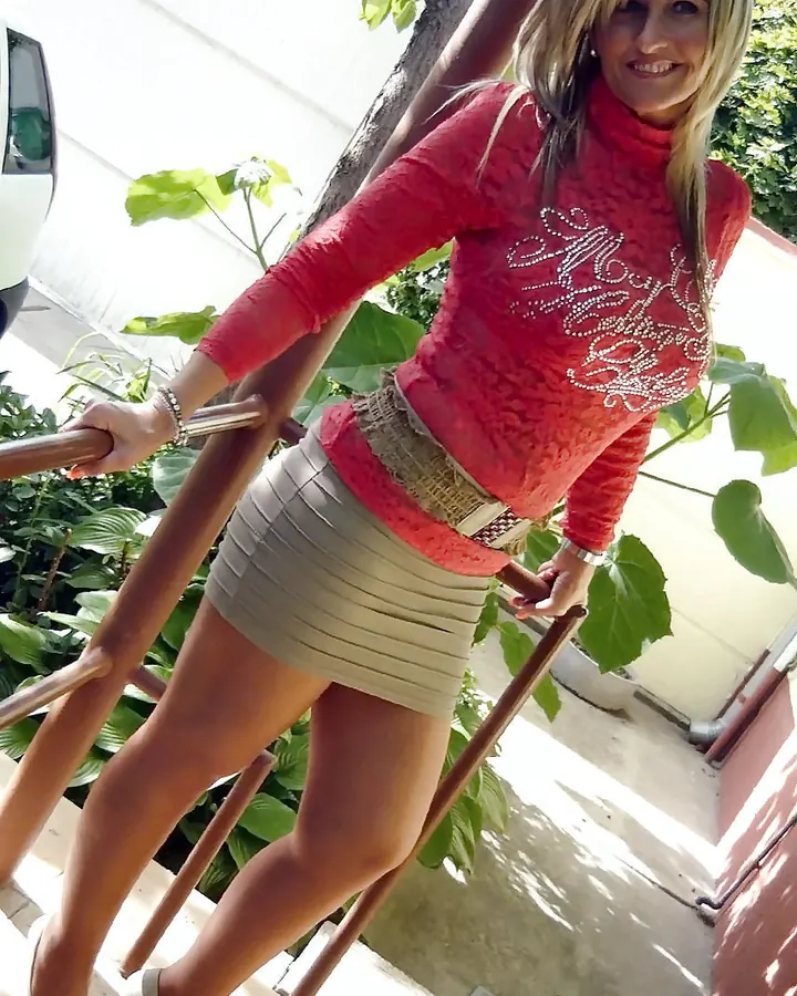 Femme aux cheveux blonds platine, en tenue décontractée, posant dans un cadre extérieur.