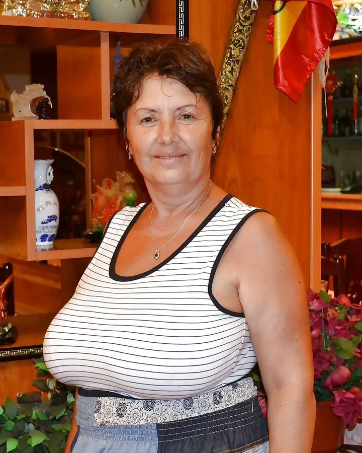 Femme latino aux cheveux châtains, portant un bonnet noir et un body noir transparent, posant près d'une porte.