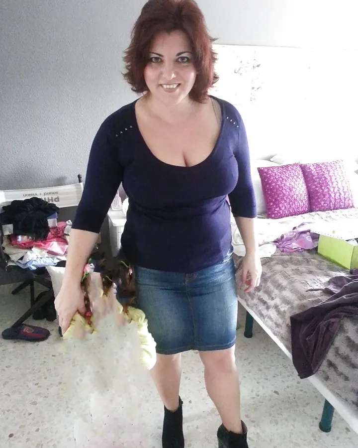 Femme rousse en jean et top marine, tenant un vêtement de lingerie jaune
